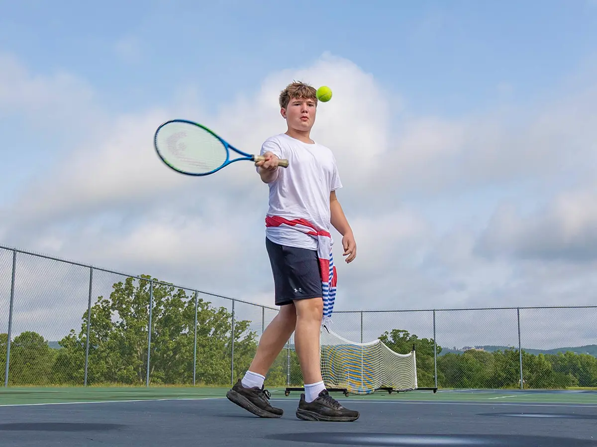 A camper playing tennis at Brookhill Ranch